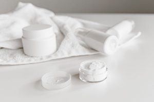 Białe słoiczki z kremem i ręcznik – krem do twarzy z ceramidami