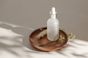 Matowa butelka z pipetą na drewnianej podstawce – serum do twarzy