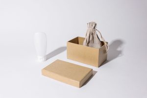 Biała butelka kosmetyku i kartonowe pudełko wysyłkowe – dropshipping produktów drogeryjnych