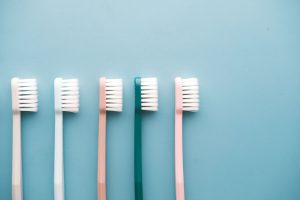 Pięć kolorowych szczoteczek do zębów na niebieskim tle – pasta wybielająca