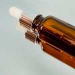 Brązowa buteleczka serum z pipetą na szklanej powierzchni – serum z retinolem