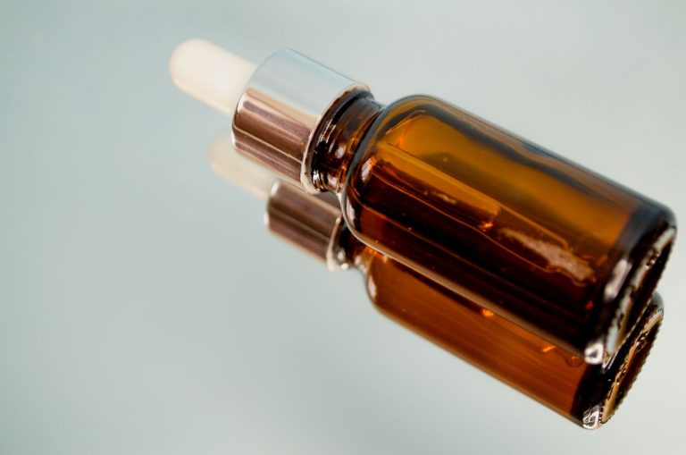 Brązowa buteleczka serum z pipetą na szklanej powierzchni – serum z retinolem