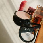 Kosmetyki do makijażu i flakon perfum w słońcu – utrwalacz makijażu w sprayu
