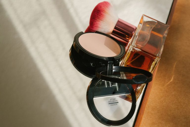 Kosmetyki do makijażu i flakon perfum w słońcu – utrwalacz makijażu w sprayu