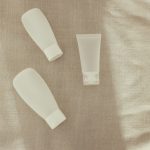 Minimalistyczne tubki kosmetyków na lnianym tle – kosmetyki dla nastolatki